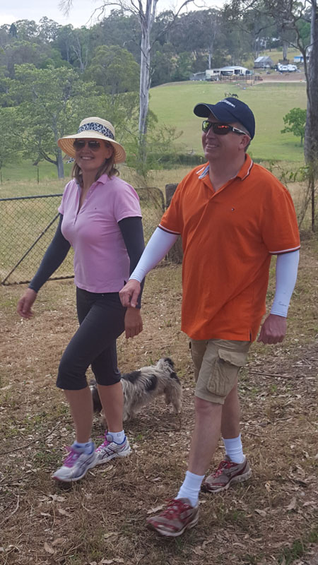 A couple out for a walk with their dog, and both the man and the woman are wearing IceRays Sun Sleeves for Maximum UV sun protection while hiking.  