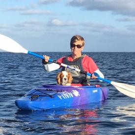 A woman kayaking with her dog and wearing IceRays Sun Sleeves for Maximum UV sun protection while paddling on the water. Kayaking A woman kayaking with her dog and wearing IceRays Sun Sleeves for Maximum UV sun protection while paddling on the water. Kayaking